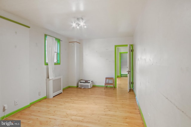 unfurnished room featuring radiator heating unit and wood-type flooring