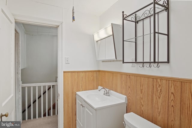 bathroom with vanity, wood walls, and toilet