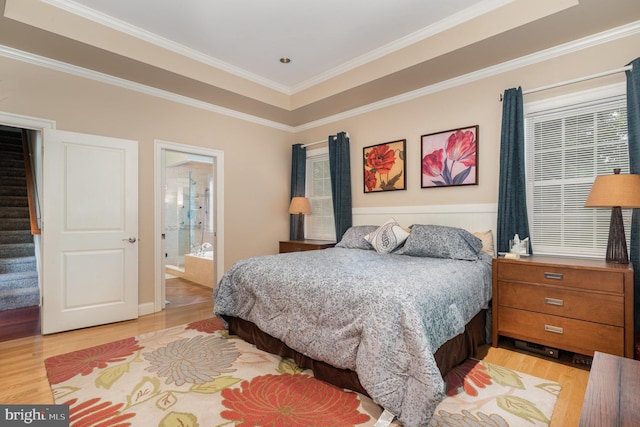 bedroom featuring a raised ceiling, ornamental molding, connected bathroom, and light hardwood / wood-style flooring