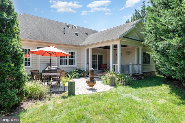 rear view of property featuring a yard, a patio area, and an outdoor fire pit