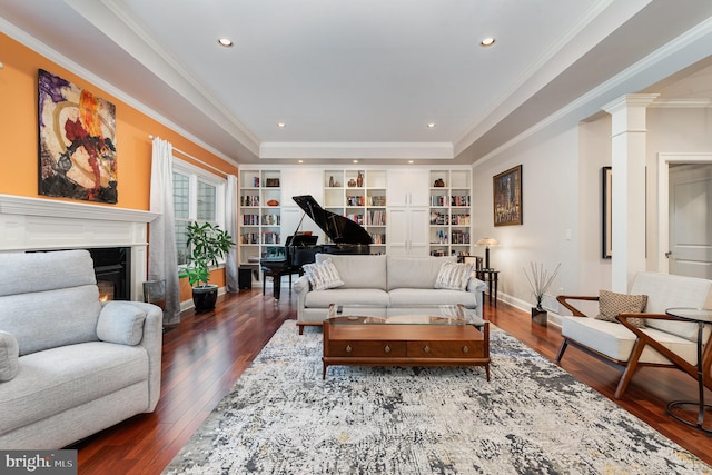 living room featuring ornate columns, crown molding, dark wood-type flooring, and built in shelves