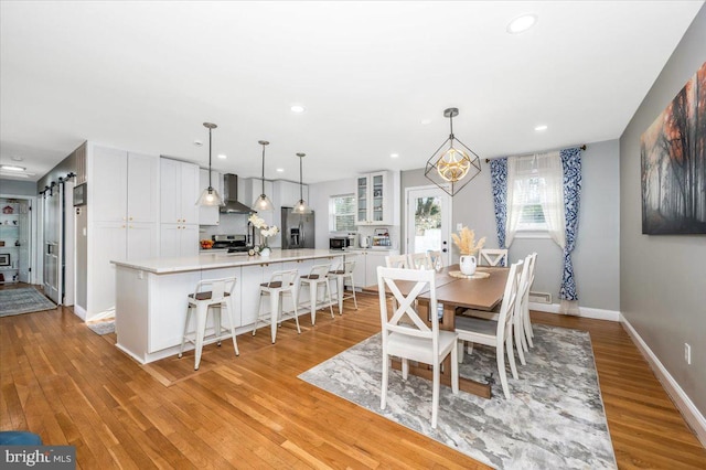 dining room featuring light wood-style floors, a barn door, baseboards, and recessed lighting