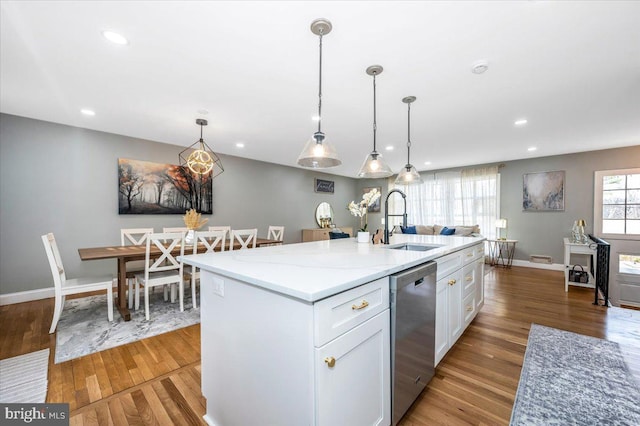 kitchen featuring a sink, white cabinetry, stainless steel dishwasher, a center island with sink, and decorative light fixtures