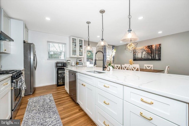 kitchen featuring glass insert cabinets, light stone countertops, stainless steel appliances, white cabinetry, and a sink