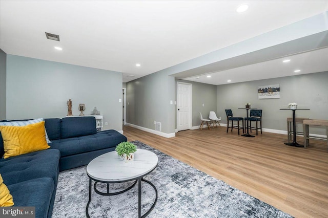 living area with light wood-style floors, recessed lighting, visible vents, and baseboards