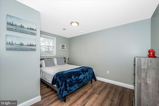 bedroom with dark wood-style floors, visible vents, and baseboards