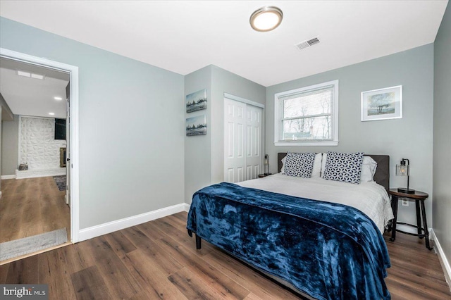 bedroom featuring dark wood-type flooring, a closet, visible vents, and baseboards