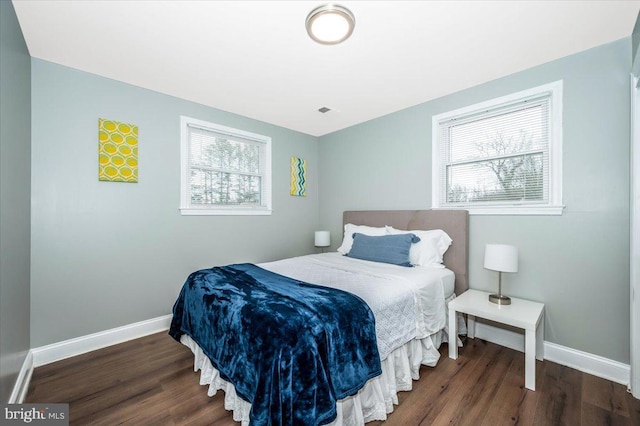 bedroom with dark wood-style flooring, visible vents, and baseboards