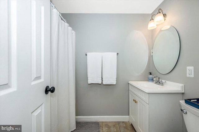 bathroom featuring toilet, tile patterned floors, vanity, and baseboards