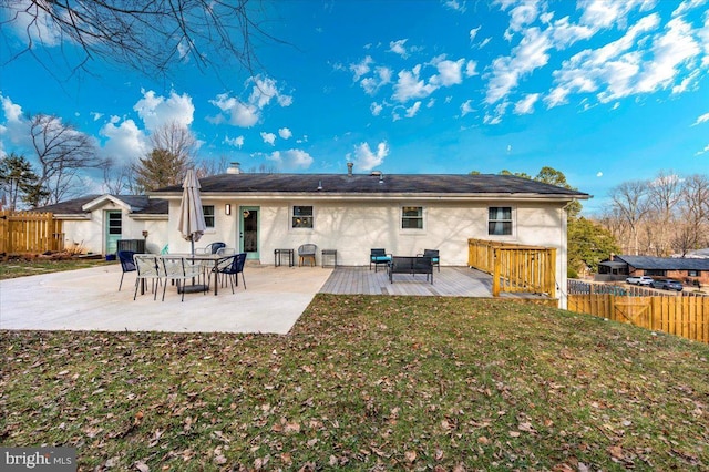 back of property featuring a chimney, fence, a lawn, and a patio