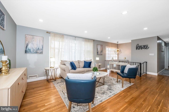 living area with light wood finished floors, visible vents, baseboards, and recessed lighting