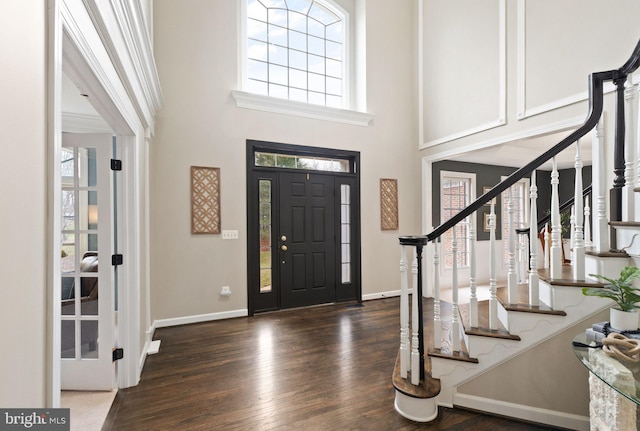 foyer entrance with a towering ceiling and dark hardwood / wood-style floors