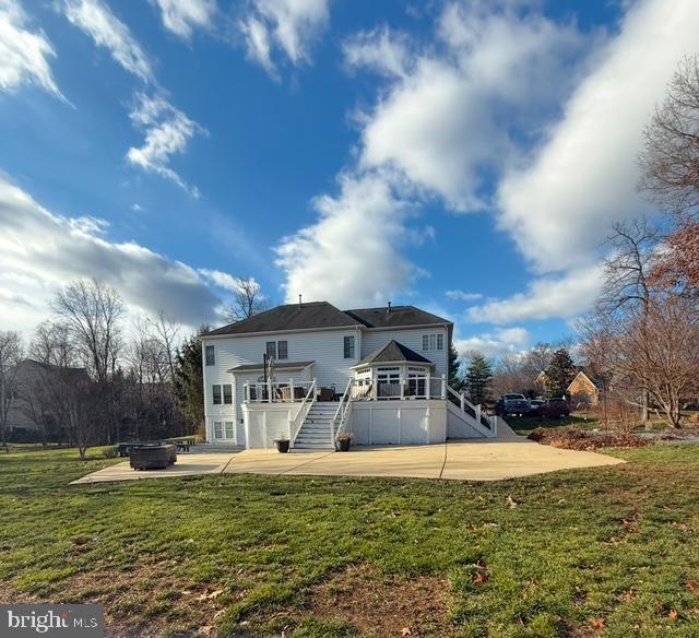 back of property with a patio, a yard, a deck, and an outdoor fire pit