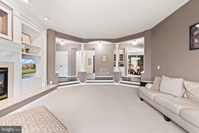 carpeted living room featuring an inviting chandelier, a fireplace, built in features, and ornate columns