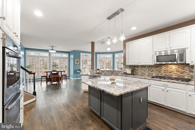 kitchen featuring white cabinetry, hanging light fixtures, stainless steel appliances, and a center island