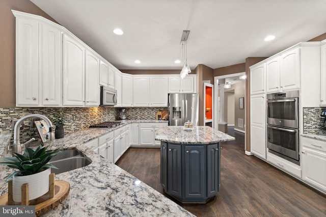 kitchen featuring hanging light fixtures, light stone countertops, appliances with stainless steel finishes, and a kitchen island