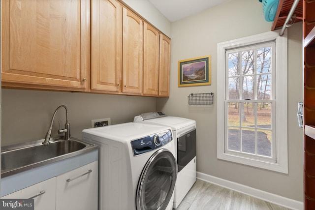 laundry room with cabinets, a healthy amount of sunlight, sink, and washer and clothes dryer