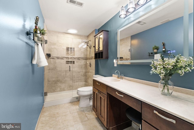 bathroom featuring tile patterned floors, vanity, toilet, and a shower with door