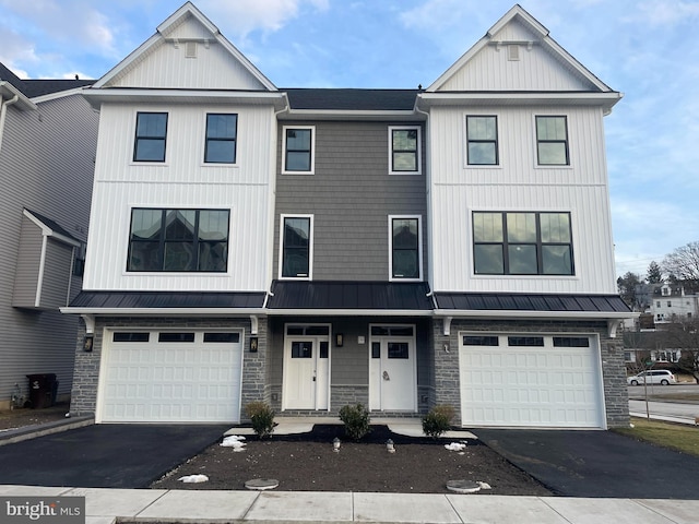 townhome / multi-family property with a garage, a standing seam roof, and driveway