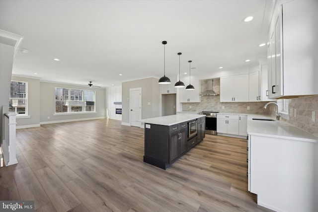 kitchen with white cabinets, open floor plan, light countertops, a center island, and wall chimney exhaust hood