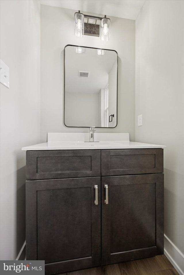 bathroom with wood finished floors, vanity, visible vents, and baseboards