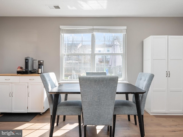 dining space featuring light wood finished floors and visible vents