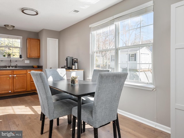 dining room featuring light wood-style floors, visible vents, and baseboards