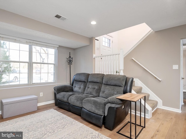 living area featuring light wood-type flooring, baseboards, stairs, and visible vents