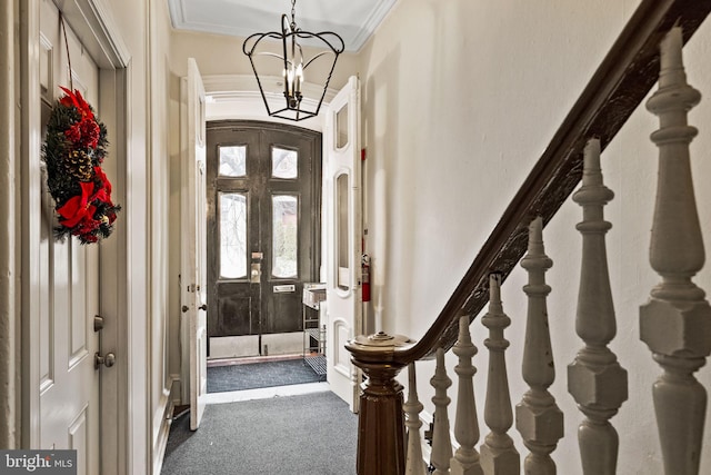 entrance foyer with french doors, ornamental molding, an inviting chandelier, and dark colored carpet