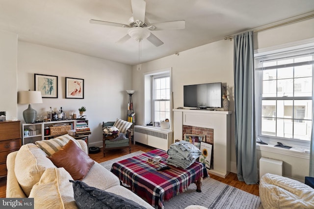 living room with ceiling fan, wood-type flooring, radiator, and a brick fireplace