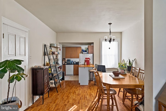 dining space with light wood-type flooring and an inviting chandelier