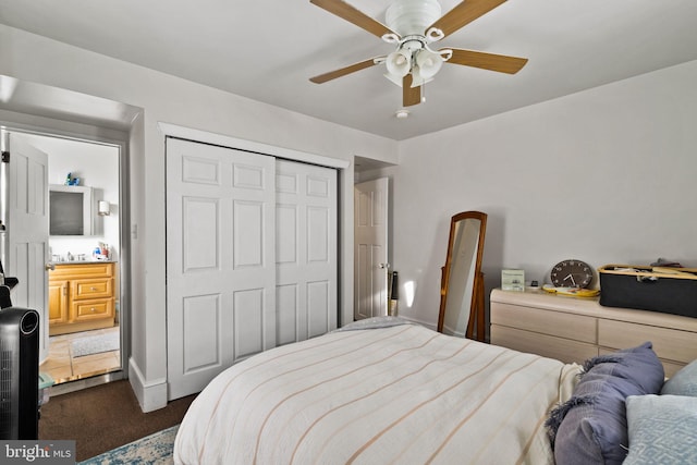 bedroom with ceiling fan, ensuite bath, dark carpet, and a closet