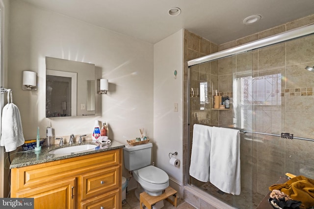 bathroom with vanity, toilet, and a shower with shower door