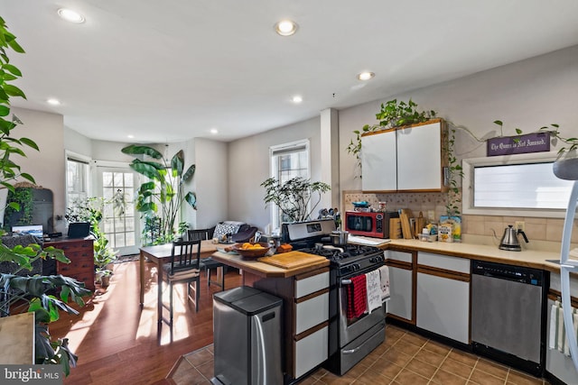 kitchen featuring white cabinetry, backsplash, a healthy amount of sunlight, and appliances with stainless steel finishes