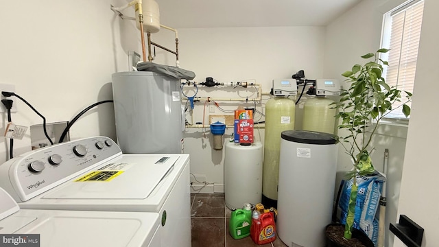 laundry area featuring electric water heater, washer and dryer, and dark tile patterned flooring