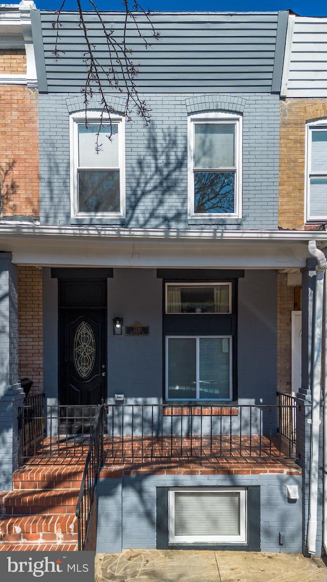 property entrance with covered porch and brick siding