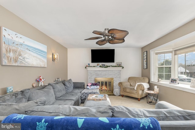 carpeted living room with a brick fireplace and ceiling fan