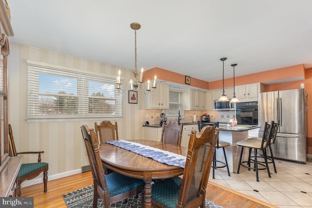 dining space featuring an inviting chandelier, sink, and light wood-type flooring