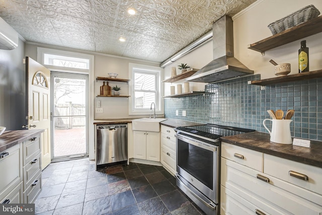 kitchen featuring an ornate ceiling, stainless steel appliances, wall chimney range hood, open shelves, and a sink