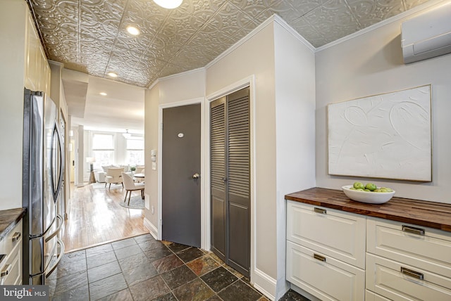 hallway with an ornate ceiling, a wall unit AC, crown molding, and baseboards