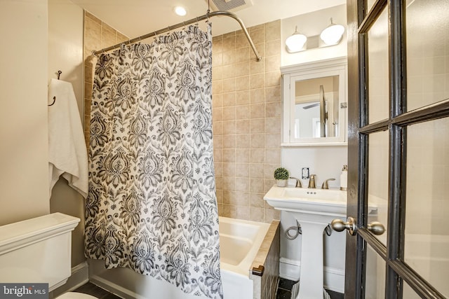 bathroom featuring tiled shower / bath, toilet, and visible vents