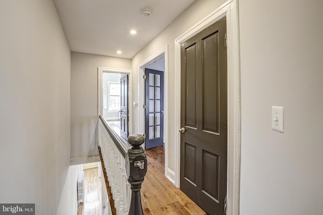 hallway with light wood finished floors, baseboards, an upstairs landing, and recessed lighting