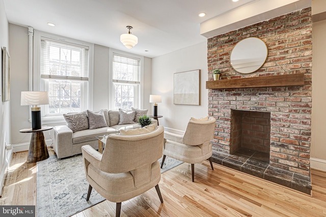 living room with a fireplace, baseboards, and wood finished floors