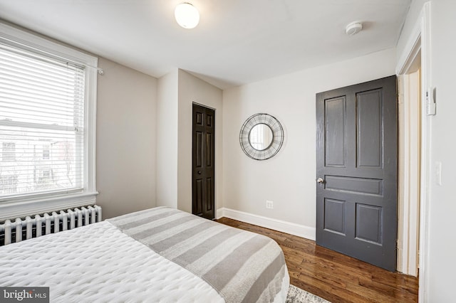 bedroom with radiator heating unit, dark wood finished floors, and baseboards