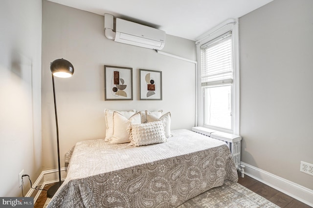 bedroom featuring an AC wall unit, dark wood finished floors, and baseboards