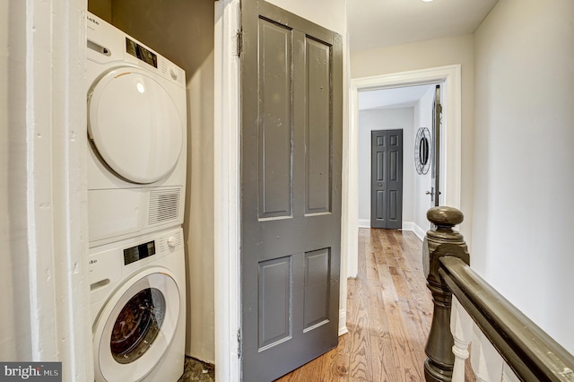 laundry room featuring laundry area, light wood-style flooring, and stacked washer and clothes dryer