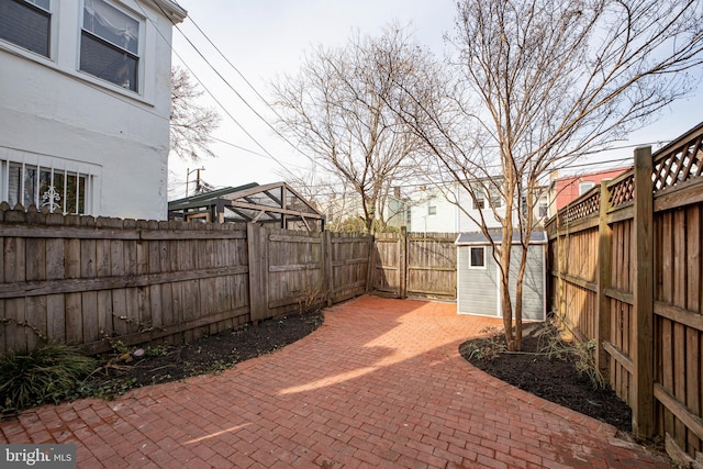 view of patio featuring an outbuilding, a storage unit, and a fenced backyard