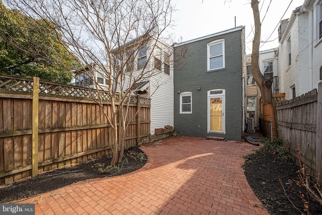 rear view of house featuring brick siding, a patio area, and a fenced backyard