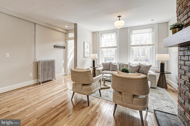 living room with light wood-type flooring, radiator, and baseboards