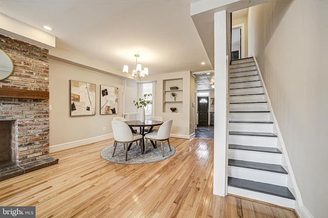 dining space with baseboards, wood-type flooring, stairs, built in shelves, and a fireplace